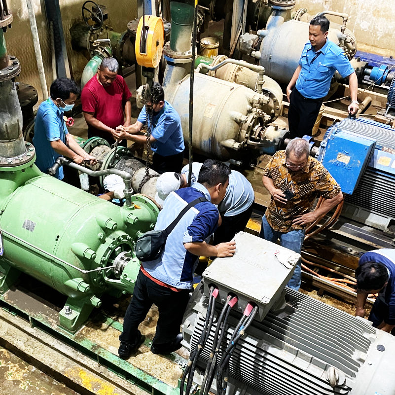 PT SJU technicians working on industrial water pumps in a factory setting